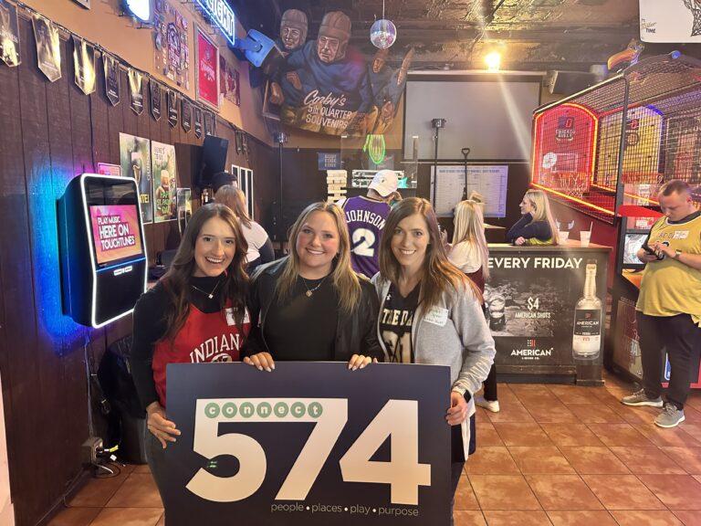 Three Connect 574 members hold the sign at the March Madness social party at Corby's Irish Pub